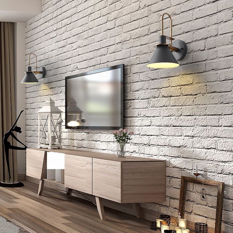 Clérachic Morandi horn-shade wall sconces in gray, mounted either side of a wall-hung TV on white painted brick in the living room.