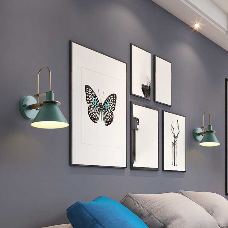 Green Clérachic Morandi horn-shade wall sconces bracketing a gallery wall of framed prints above a bed, lighting the pictures from each side.