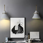 White Clérachic Morandi horn-shade wall sconces either side of a framed ink print above a desk, each washing the dark grey wall below.