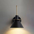 Head-on view of the black Clérachic Morandi horn-shade wall sconce lit on a grey wall, the cream interior throwing light straight down.