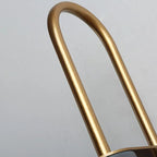 Macro of the brushed brass arch on the Clérachic Morandi horn-shade wall sconce, its grain visible along the curve above the shade.