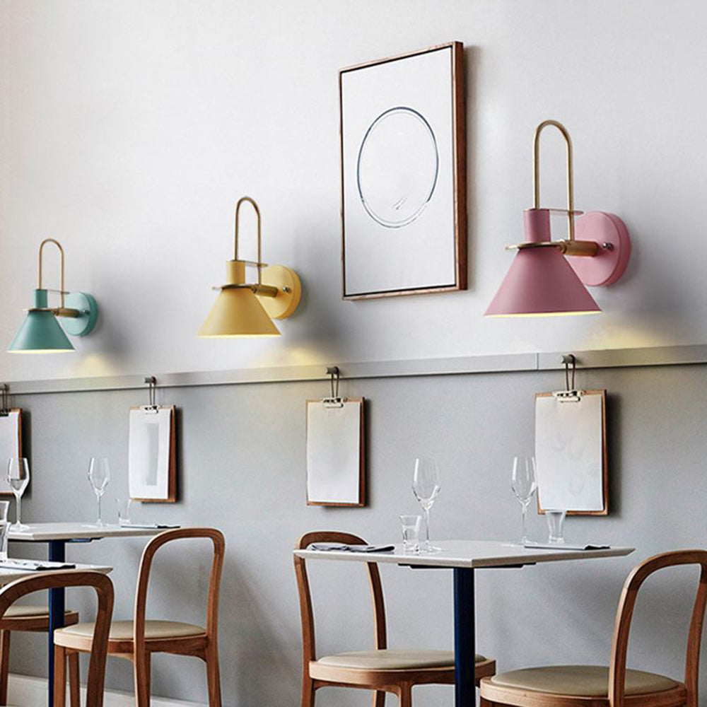 Green, yellow and pink Clérachic Morandi horn-shade wall sconces lined along a café wall above bistro tables and hanging menu boards.