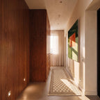 Clérachic square wall lights glowing low along a hallway beside walnut panelling and a chequered runner.