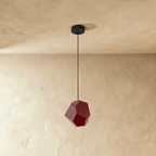 Side view of the Clérachic rose red glass pendant shows its angular cut facets catching light on plaster walls.