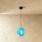 This Clérachic pendant's blue faceted glass glows from within, the bulb visible through its angled panes.