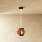 This Clérachic pendant's amber-brown faceted glass glows warmly, the bulb visible through its angled panes.