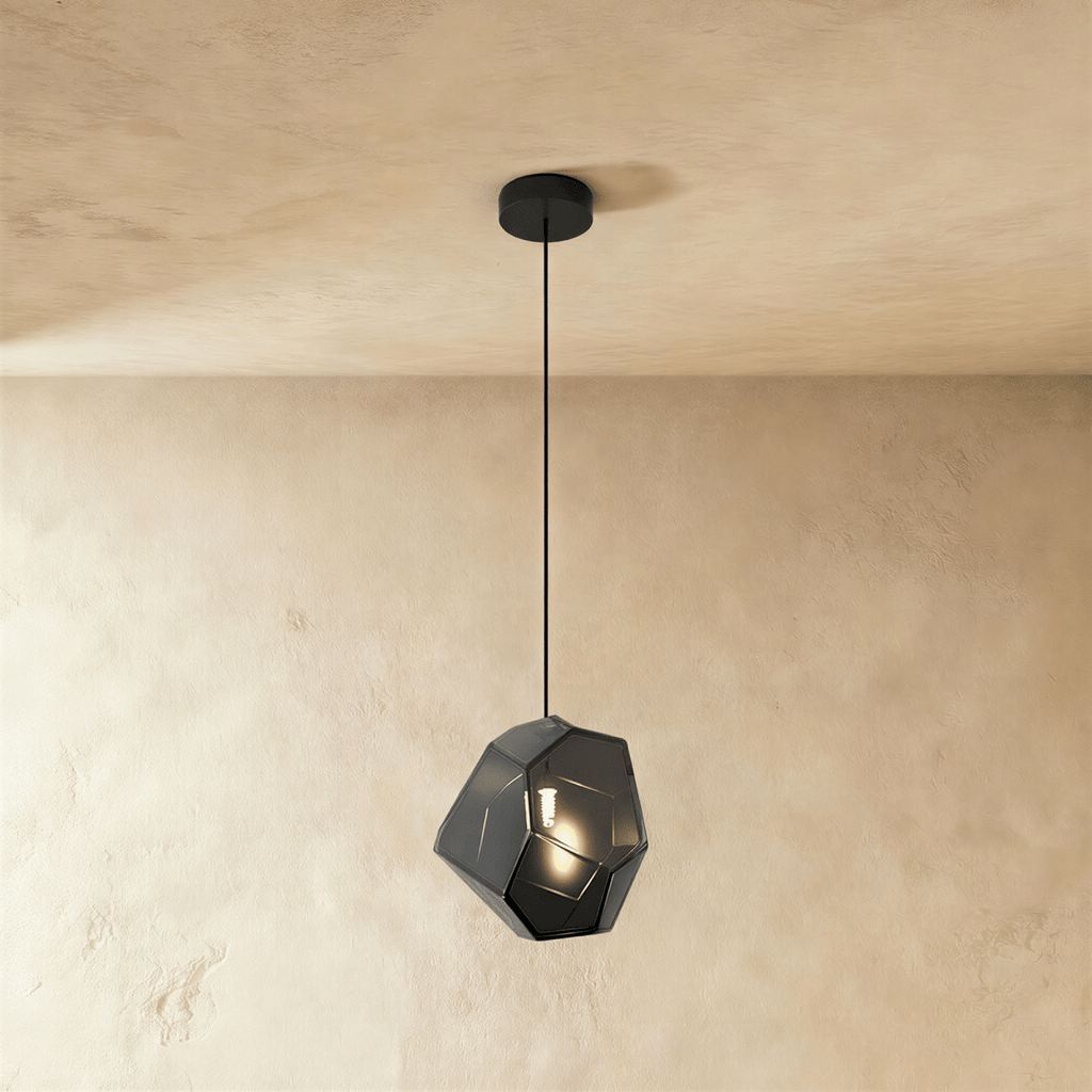 This Clérachic pendant's light gray faceted glass glows softly, the bulb visible through its angled panes.