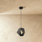 This Clérachic pendant's light gray faceted glass glows softly, the bulb visible through its angled panes.