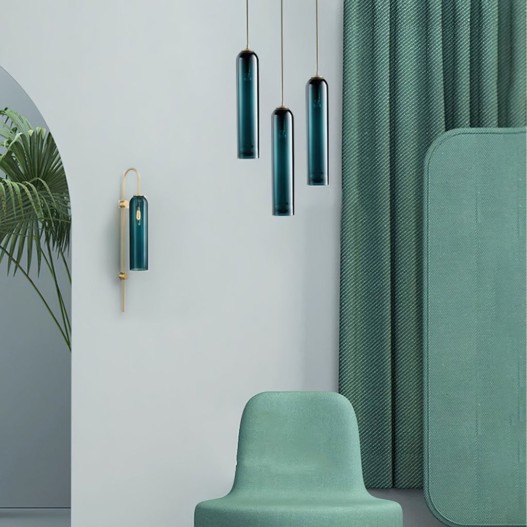A closer view of the staggered green Clérachic pendants and wall sconce against the green curtain and armchair.