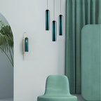 A closer view of the staggered green Clérachic pendants and wall sconce against the green curtain and armchair.