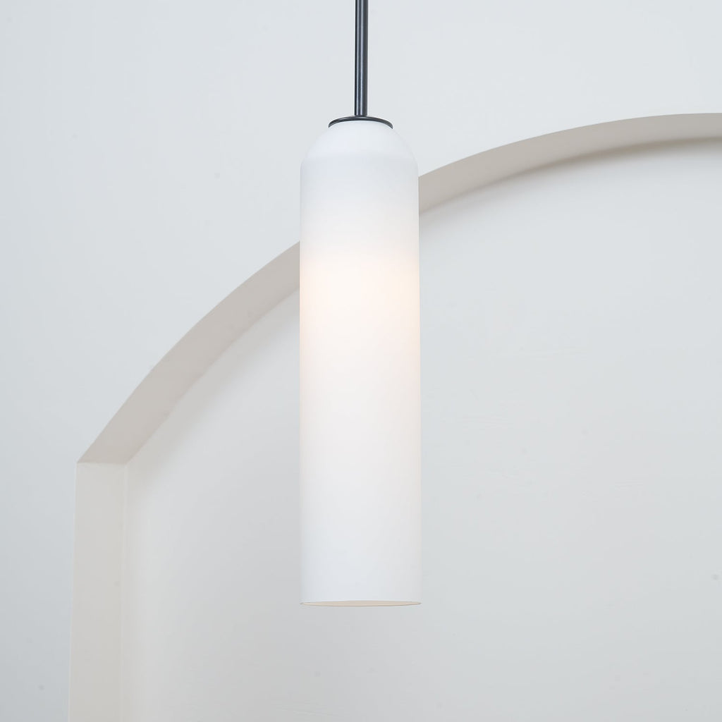 A closer crop of the frosted white Clérachic pendant on its black rod, framed against the pale arch behind it.