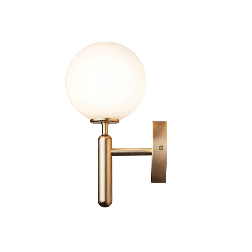 Unlit, this brass Clérachic wall light shows its round white glass globe against a plain white background.