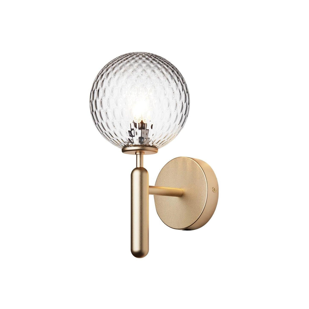 Softly glowing, this brass Clérachic wall light's dimpled clear glass globe stands out against a plain white background.