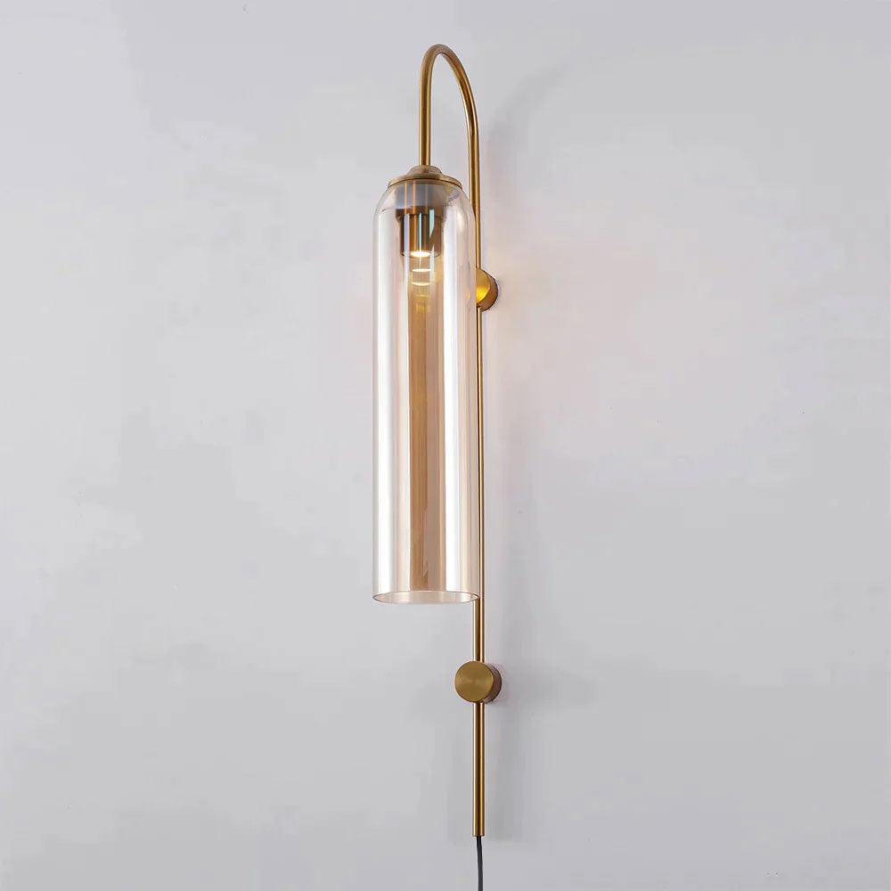 Amber glass on the Clérachic mouth-blown wall sconce, the lit cylinder warming to honey against a pale grey wall.