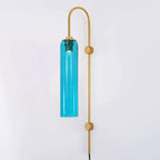 Sky blue glass on the Clérachic mouth-blown wall sconce with a gold body, lit and photographed against a plain white wall.
