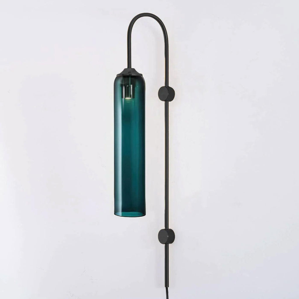 Deep teal glass on the black-bodied Clérachic mouth-blown wall sconce, shown unlit against a plain pale wall.