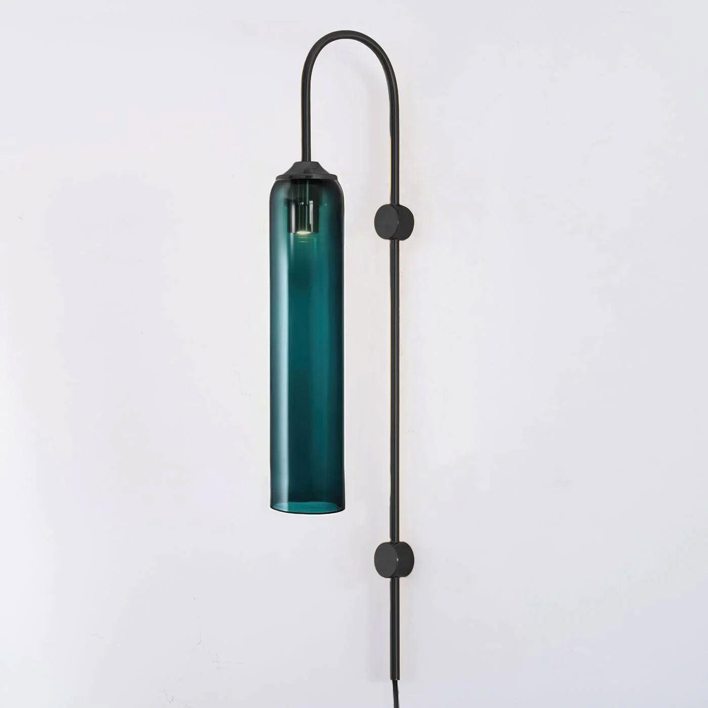 Deep teal glass on the black-bodied Clérachic mouth-blown wall sconce, shown unlit against a plain pale wall.
