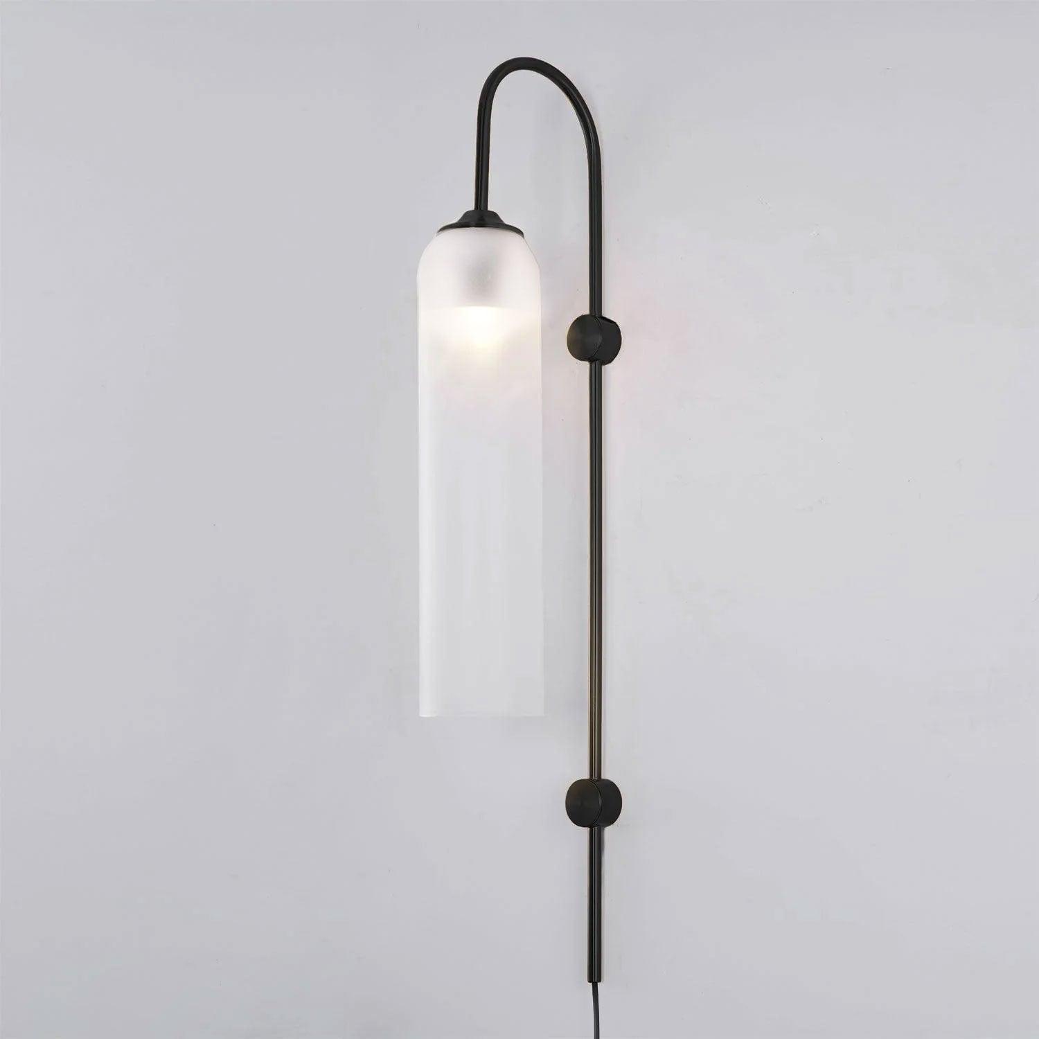 Frosted white glass on the black Clérachic mouth-blown wall sconce, the bulb showing as a soft bright spot near the top.