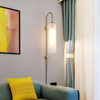 Clérachic mouth-blown glass wall sconce above a green sofa with a yellow cushion, next to framed art and green curtains.
