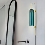 Clérachic mouth-blown glass wall sconce in teal lighting a bathroom wall beside a black arched mirror and matt black tap.
