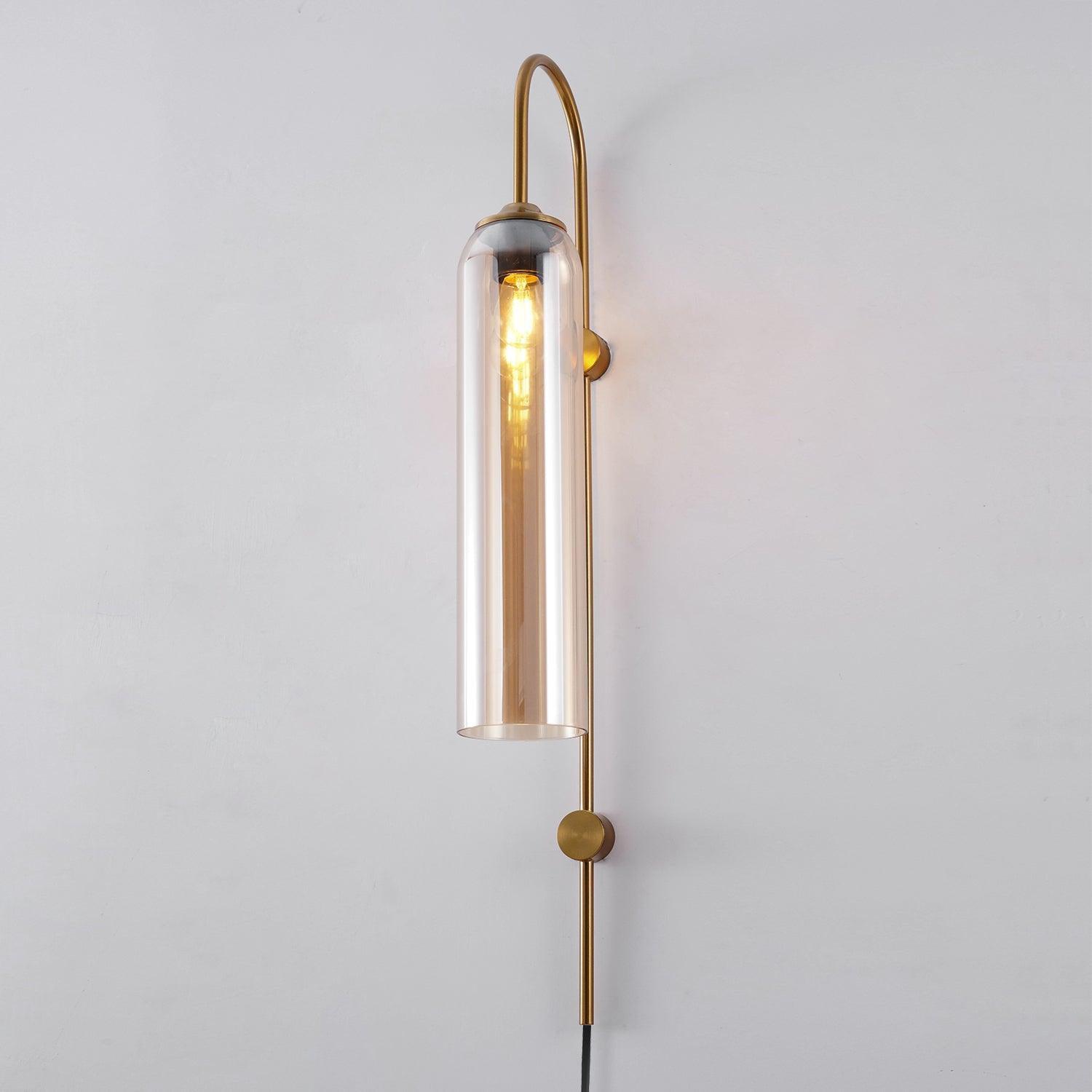 Clérachic mouth-blown glass wall sconce in amber glass on gold, the long filament bulb reading clearly through the cylinder.