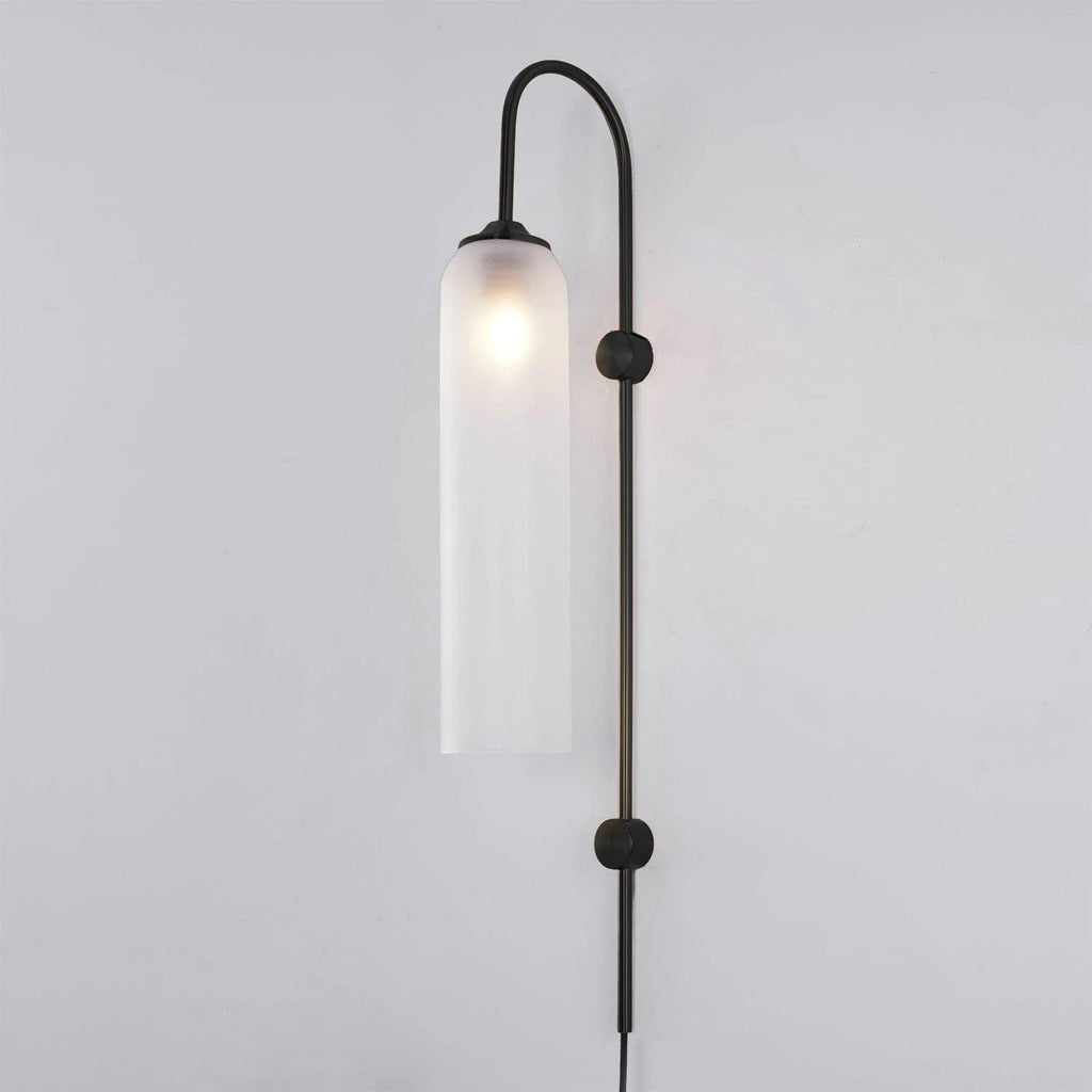 Clérachic mouth-blown glass wall sconce in frosted white on a black body, lit, against a pale studio wall.