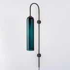 Clérachic mouth-blown glass wall sconce in deep teal on black, unlit, its gooseneck arching over the top of the shade.