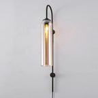 Clérachic mouth-blown glass wall sconce in amber on black, the filament running most of the length of the cylinder.