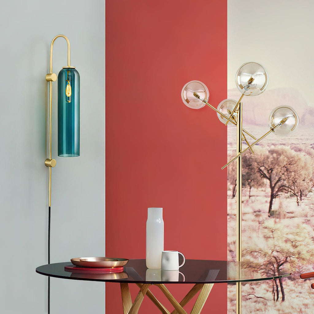 Clérachic mouth-blown glass wall sconce in teal beside a red wall and a glass table set with a copper tray.