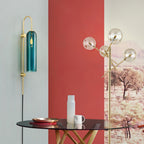 Clérachic mouth-blown glass wall sconce in teal beside a red wall and a glass table set with a copper tray.