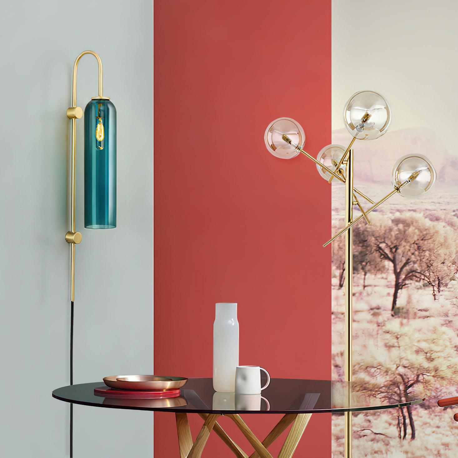Clérachic mouth-blown glass wall sconce in teal beside a red wall and a glass table set with a copper tray.