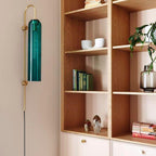 Clérachic mouth-blown glass wall sconce in emerald green on a blush wall, next to oak shelving full of books.