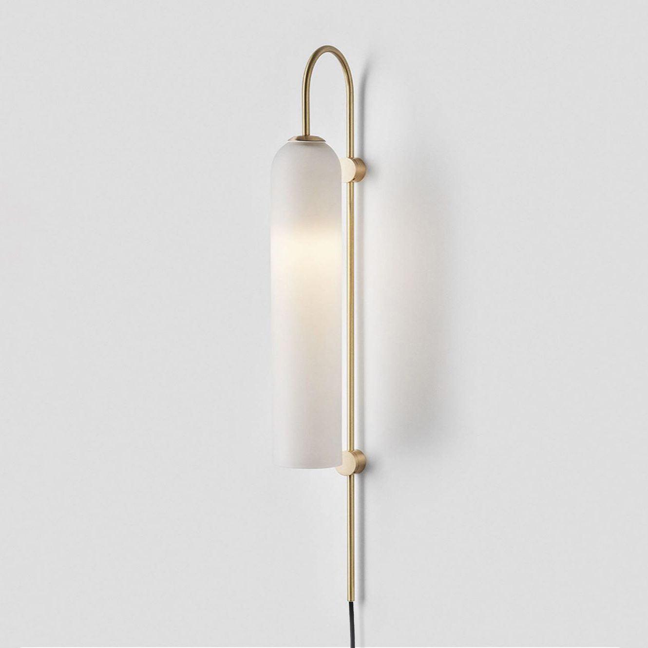 Clérachic mouth-blown glass wall sconce in frosted white on brushed gold, lit softly and casting a wide wall shadow.