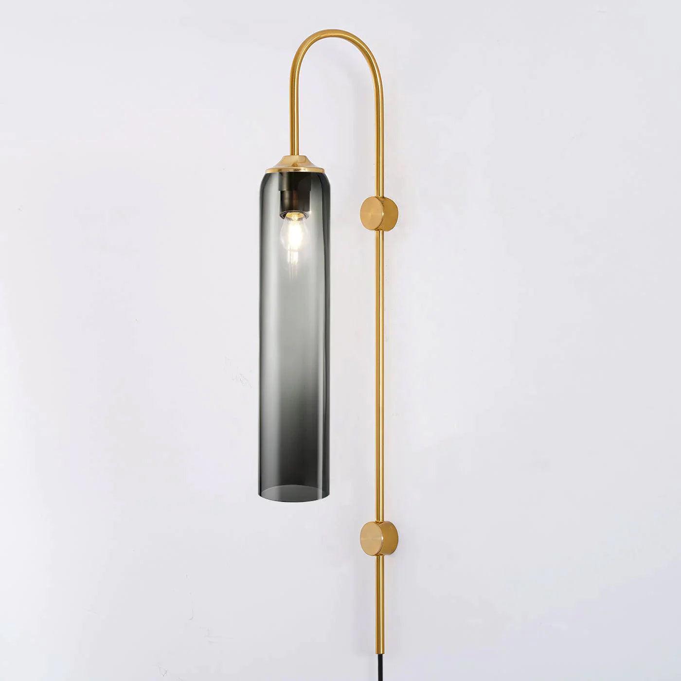 Clérachic mouth-blown glass wall sconce in smoke grey on gold, lit, the shade paling from dark cap to clear foot.