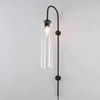 Clérachic mouth-blown glass wall sconce in clear glass on black, a round filament bulb lit inside the cylinder.