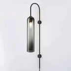 Clérachic mouth-blown glass wall sconce in smoke grey on black, lit, the bulb visible through the tinted glass.