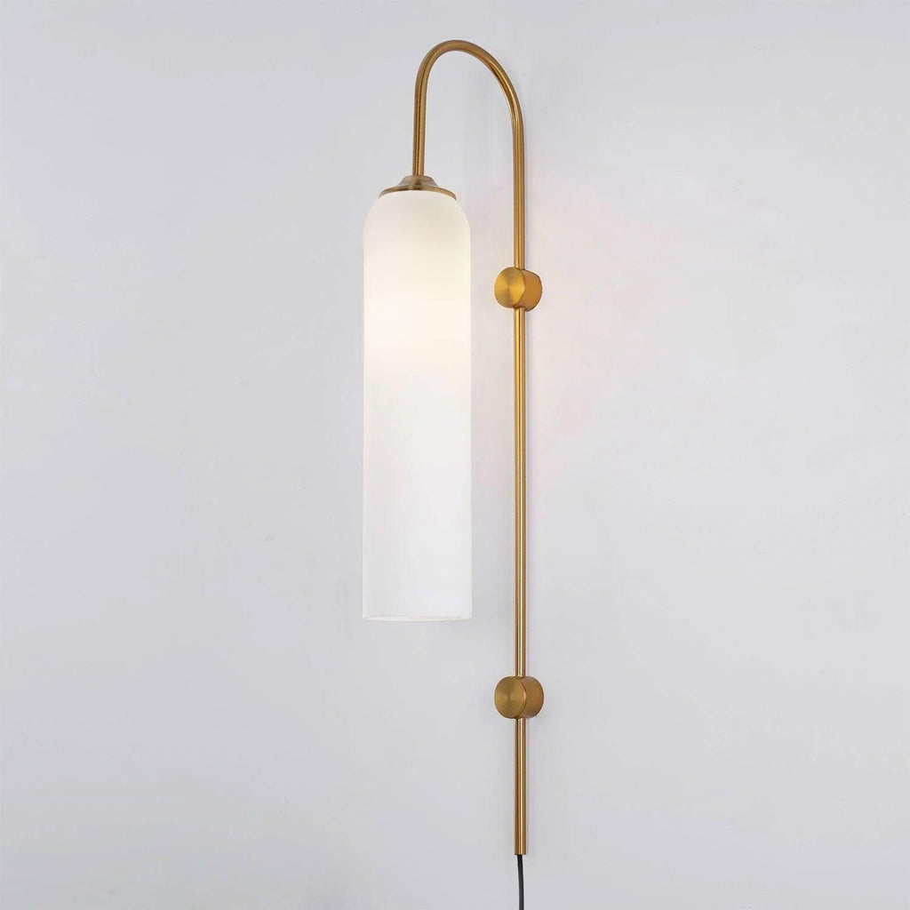 Clérachic mouth-blown glass wall sconce in opal white on gold, lit, glowing evenly from cap to open foot.