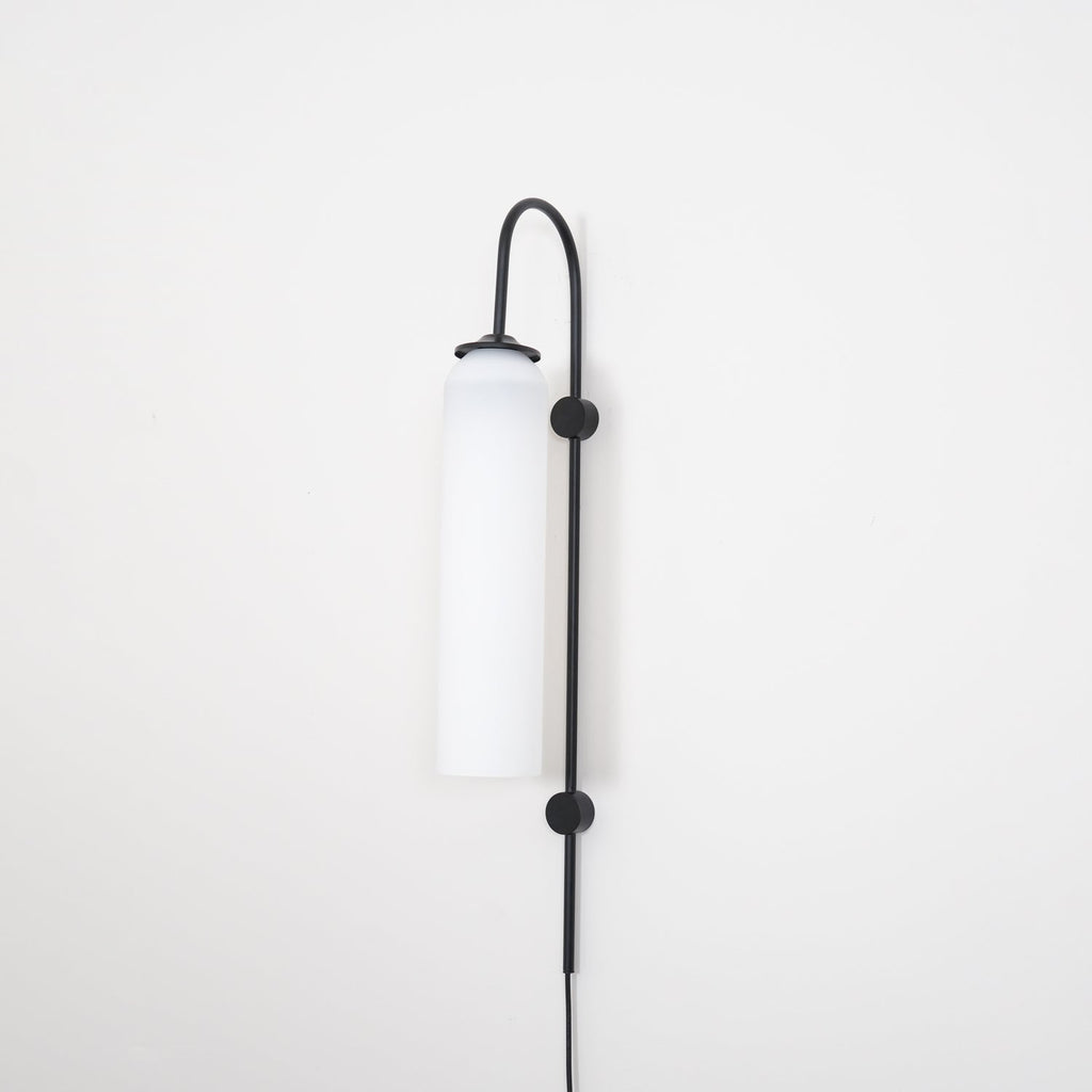 Clérachic mouth-blown glass wall sconce in opal white on black, switched off, shot square against a white wall.