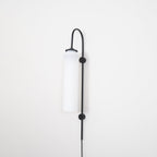 Clérachic mouth-blown glass wall sconce in opal white on black, switched off, shot square against a white wall.