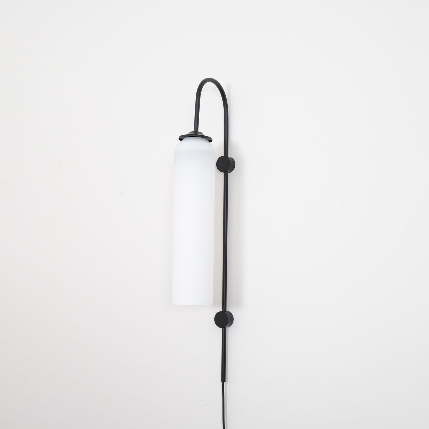 Clérachic mouth-blown glass wall sconce in opal white on black, switched off, shot square against a white wall.