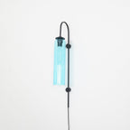 Clérachic mouth-blown glass wall sconce in sky blue on black, unlit, the glass holding its colour with no bulb lit.