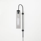 Clérachic mouth-blown glass wall sconce in smoke grey on black, unlit, the black cap and sleeve visible at the top.