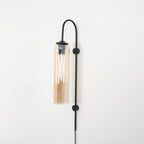 Clérachic mouth-blown glass wall sconce in amber on black, brightly lit, the whole cylinder turned honey gold.