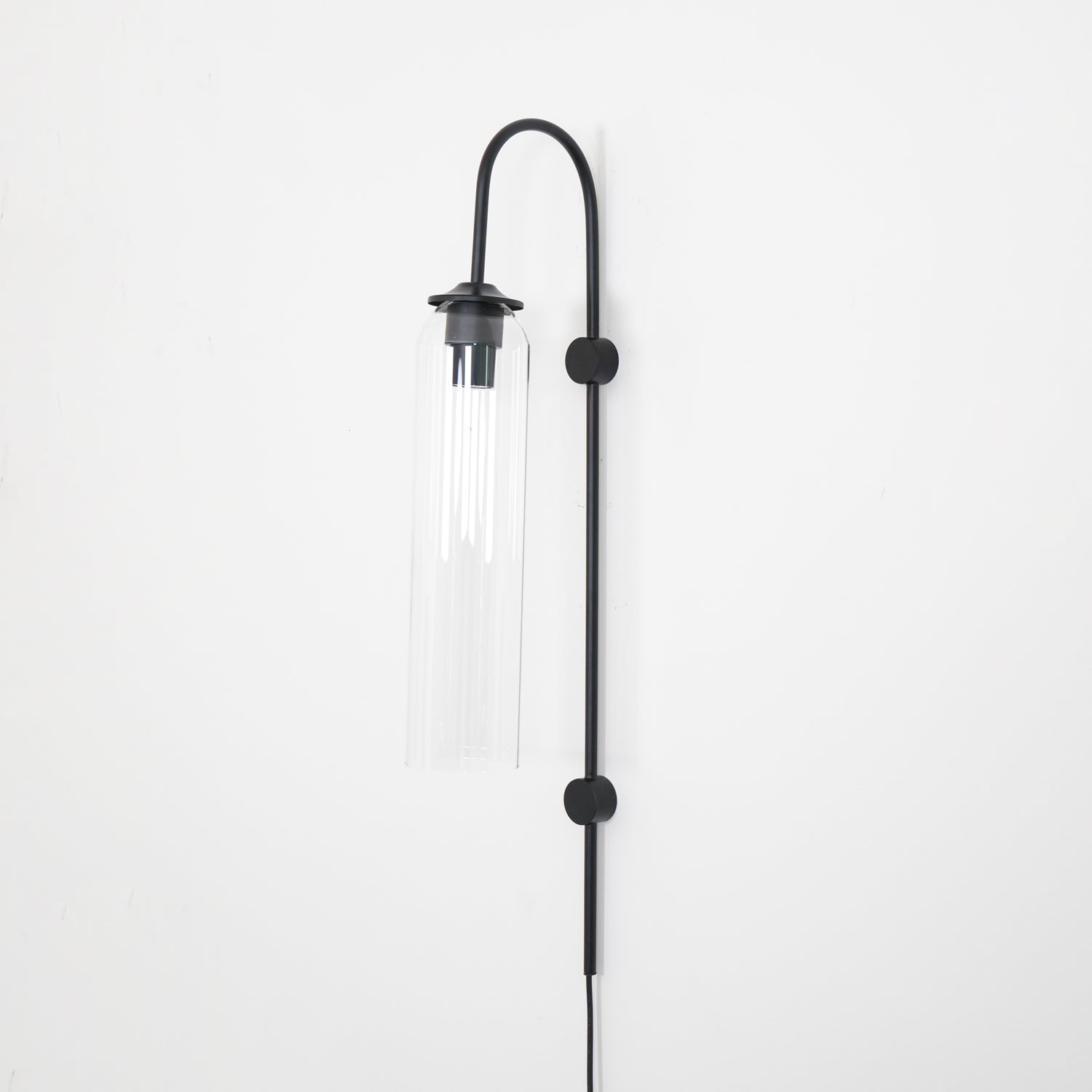 Clérachic mouth-blown glass wall sconce in clear glass on black, unlit, showing the chrome sleeve above the bulb.