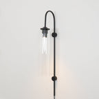 Clérachic mouth-blown glass wall sconce in clear glass on black, lit, light falling in a defined pool below the foot.