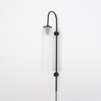 Clérachic mouth-blown glass wall sconce in frosted white on black, unlit, both disc mounts fixing the rod to the wall.