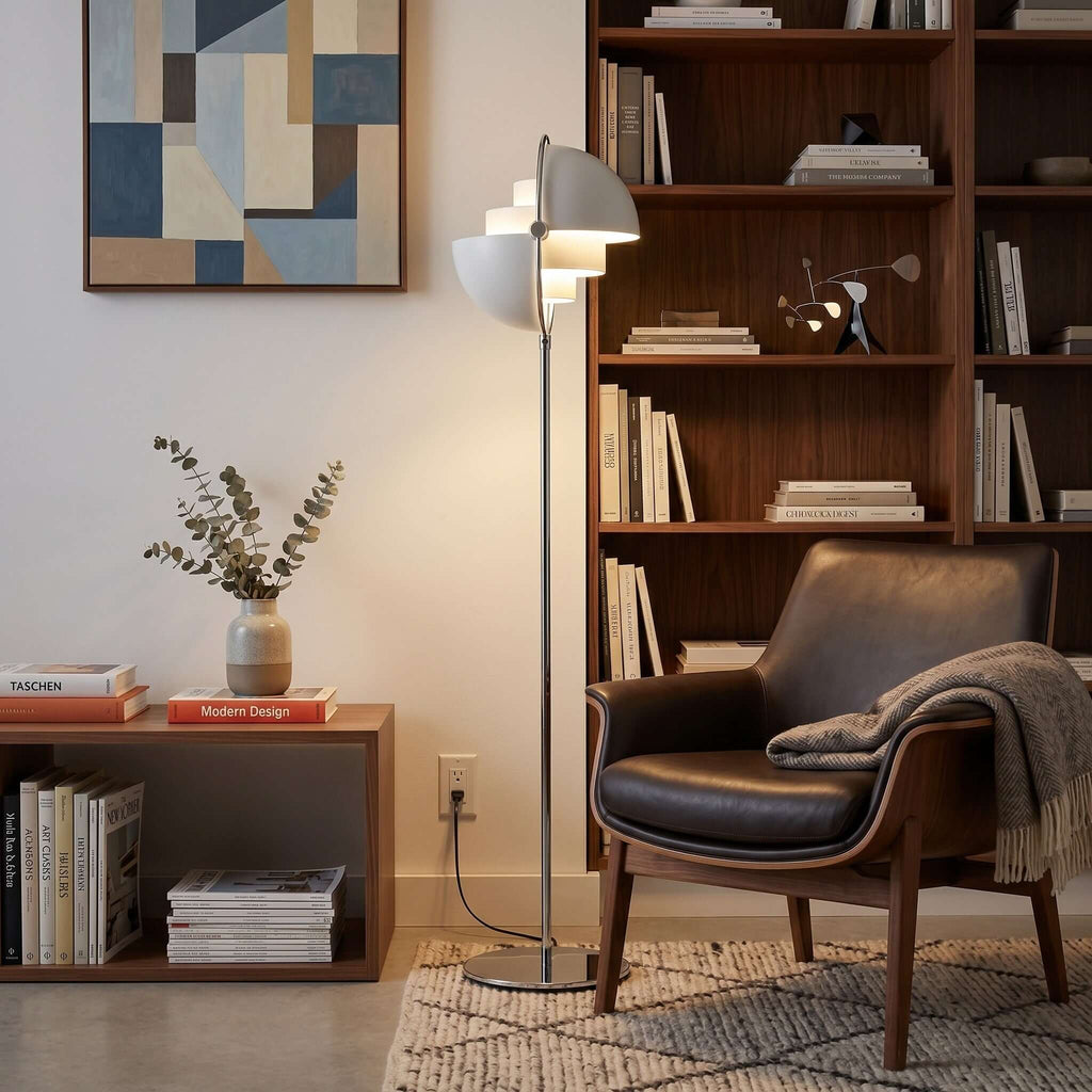 Standing beside a leather armchair and a bookcase, the Clérachic floor lamp in White & Chrome reaches above shoulder height.