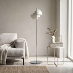 Next to a cream armchair and a small side table, this Clérachic floor lamp in White & Chrome stands on its own slim stem.
