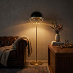 Glowing warmly in a darkened room with a leather sofa, the Clérachic floor lamp in Black & Brass lights the seat beside it.
