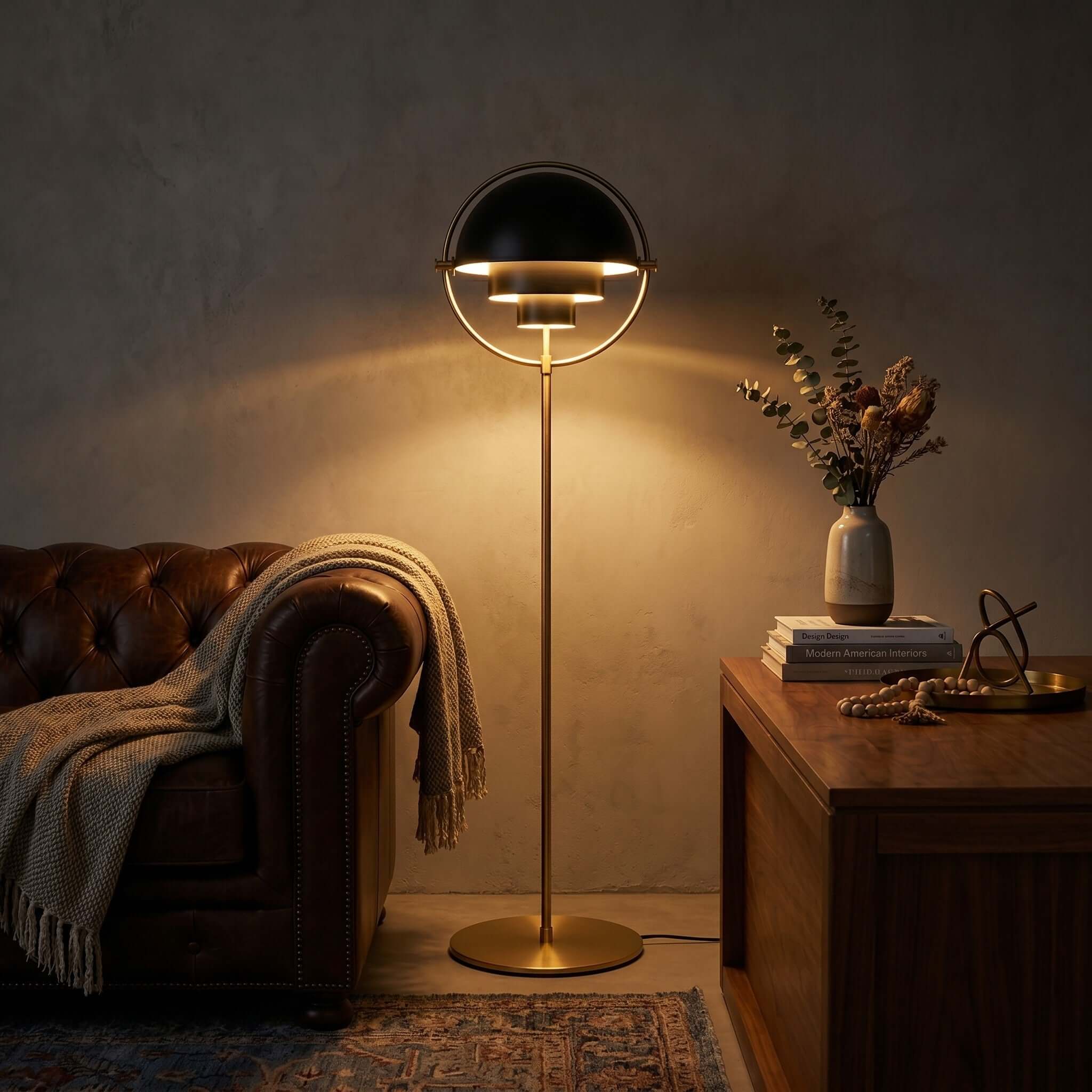 Glowing warmly in a darkened room with a leather sofa, the Clérachic floor lamp in Black & Brass lights the seat beside it.